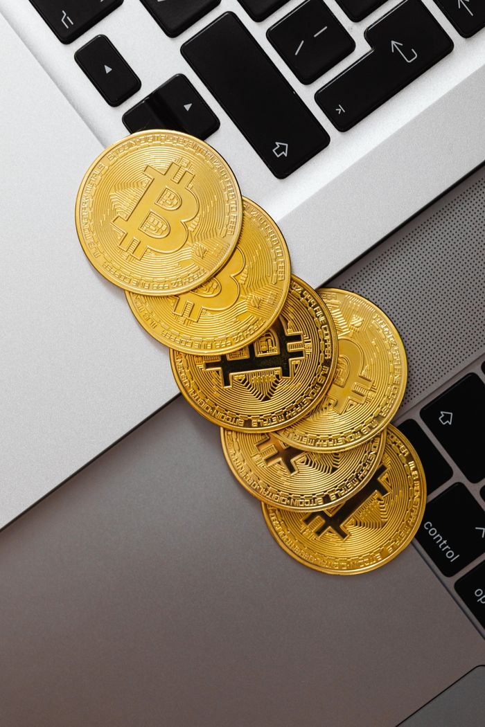 About Top view of golden bitcoins placed on a laptop keyboard, symbolizing digital currency and financial technology.