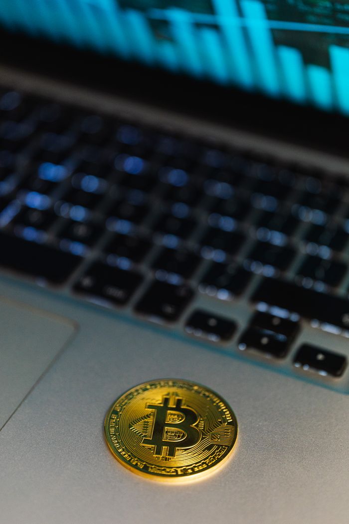 Services Close-up of a Bitcoin coin on a laptop, with a graph display in the background representing cryptocurrency technology.