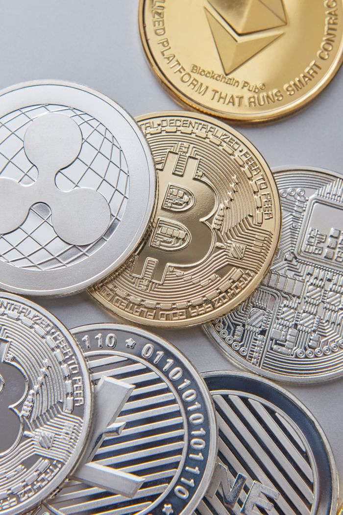 About High-resolution vertical shot of various cryptocurrency coins, emphasizing Bitcoin, Ethereum, and Ripple.