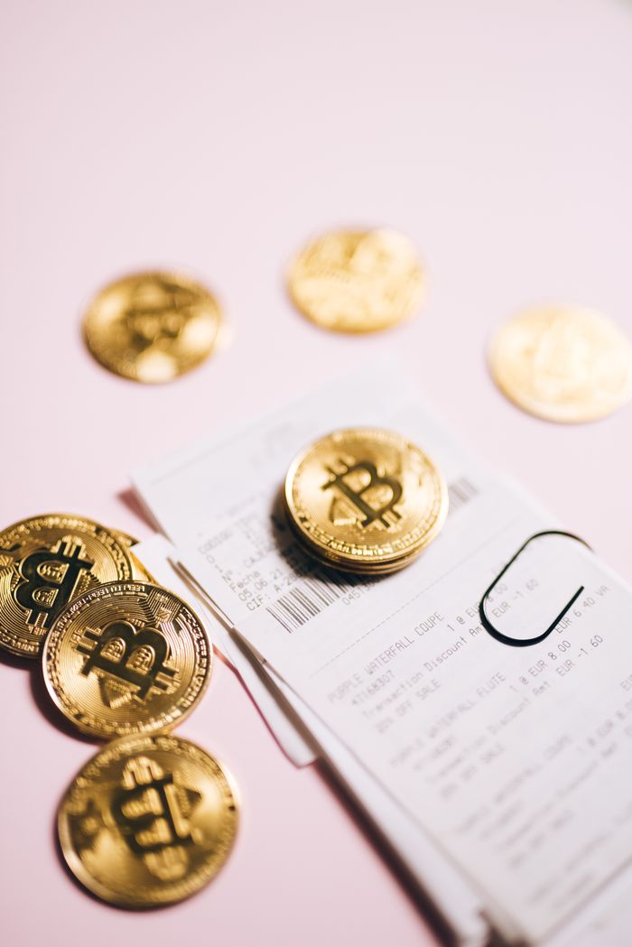 Terra Station : Security, Features, and the Future of Blockchain Wallets Close-up of Bitcoin coins and financial receipts on a pink background.